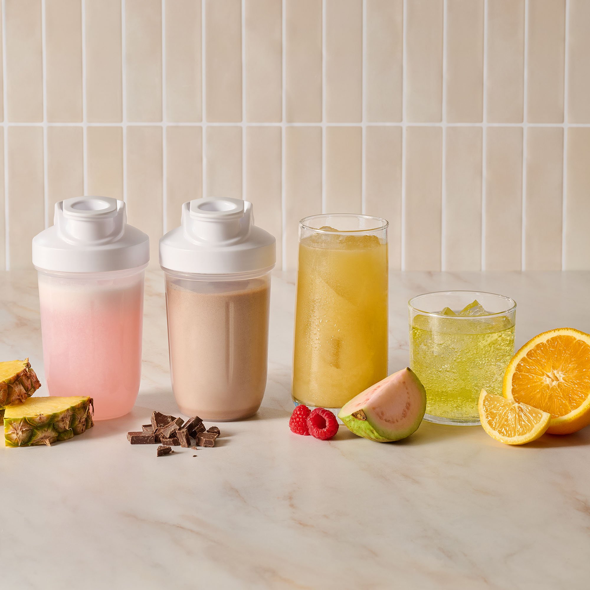 Sports and protein drinks in shakers and glasses behind fruit and chocolates.